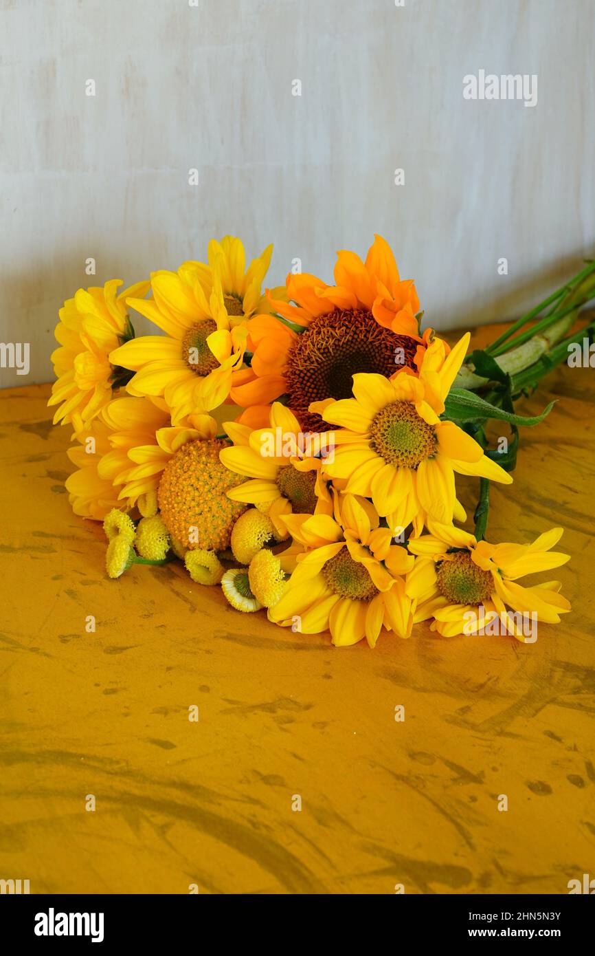 Ein Strauß gelber Blumen mit Craspedia, Gänseblümchen und Sonnenblumen Stockfoto