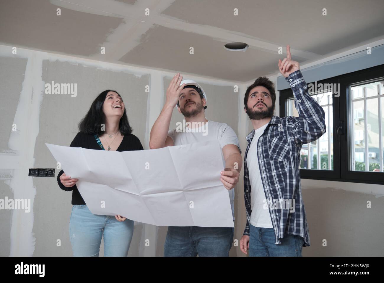 Architekt zeigt interessierten jungen Paaren Entwürfe zur Decke der Wohnung. Stockfoto
