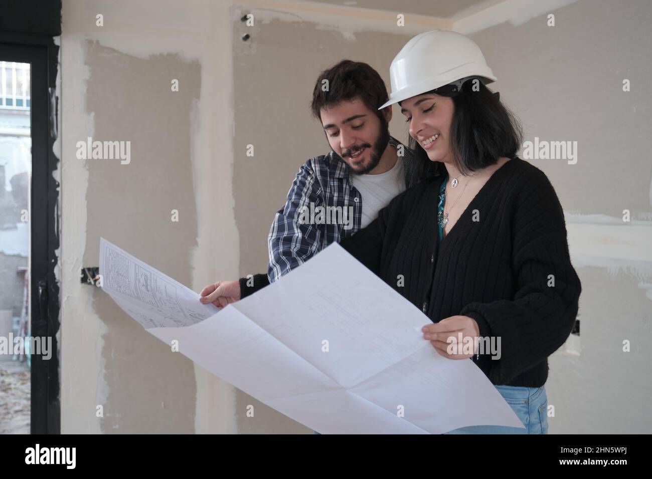 Architekt zeigt dem interessierten jungen Mann Baupläne für eine Wohnung. Stockfoto