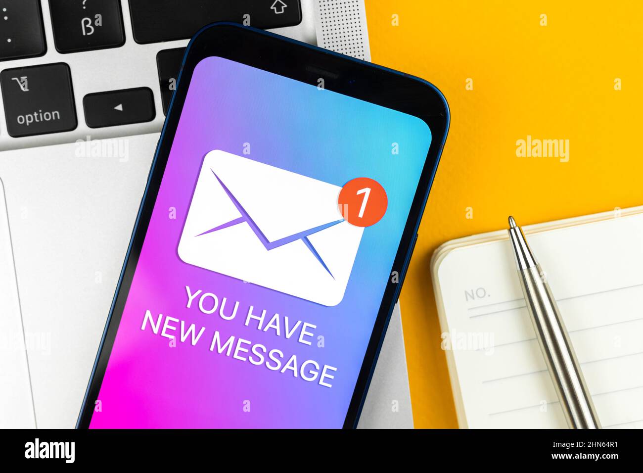 Sie haben eine neue SMS-Benachrichtigung in der Nahaufnahme eines Mobiltelefons. Geschäftskommunikationskonzept, Laptop- und Bürotisch-Hintergrund Stockfoto