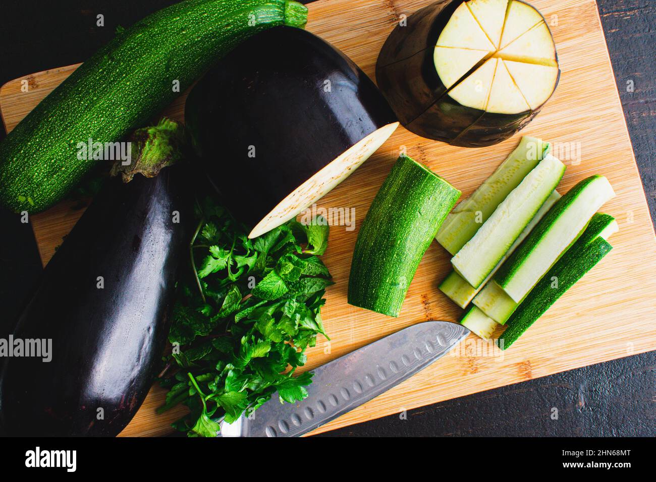 Auberginen und Zucchini in Keile schneiden: Auberginen und Zucchini-Keile auf einem Schneidebrett aus Bambusholz Stockfoto