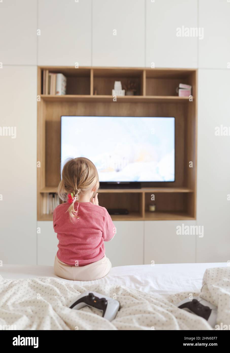 Kleines nettes Mädchen, das zu Hause Fernsehen schaut. Stockfoto