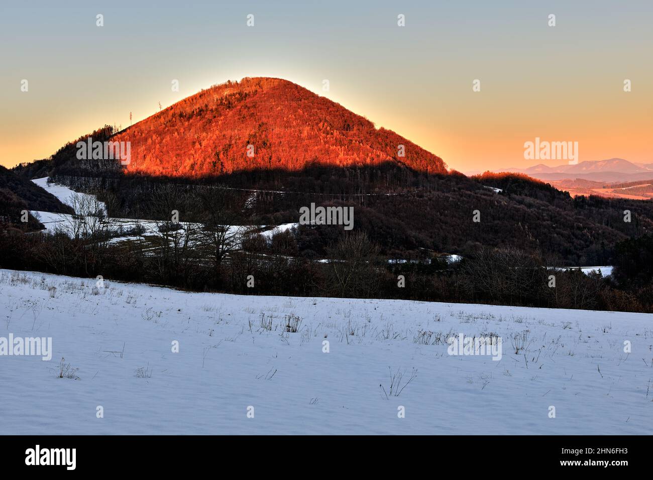Berg Winterlandschaft mit Hügeln und bunten Himmel bei Sonnenuntergang. Schöne Seitenlicht untergehende Sonne. Natürlicher Hintergrund, Tapete. Vrsatec, Slowakei. Stockfoto