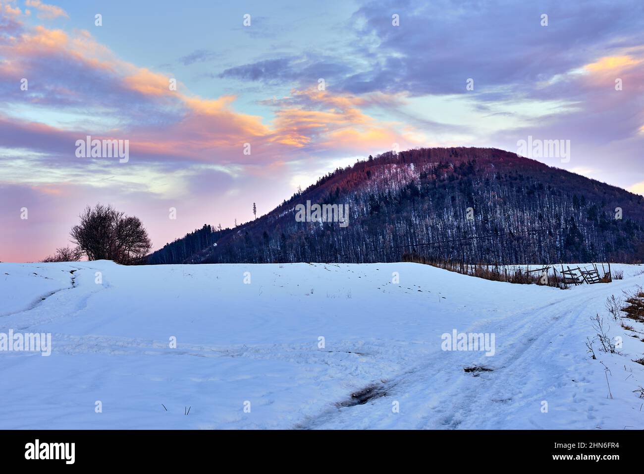 Winter Berglandschaft mit Hügel bei Sonnenuntergang. Blauer Himmel, bunte Wolken. Pfad im Vordergrund natürlicher Hintergrund, Hintergrundbild. Vrsatec, Slowakei. Stockfoto