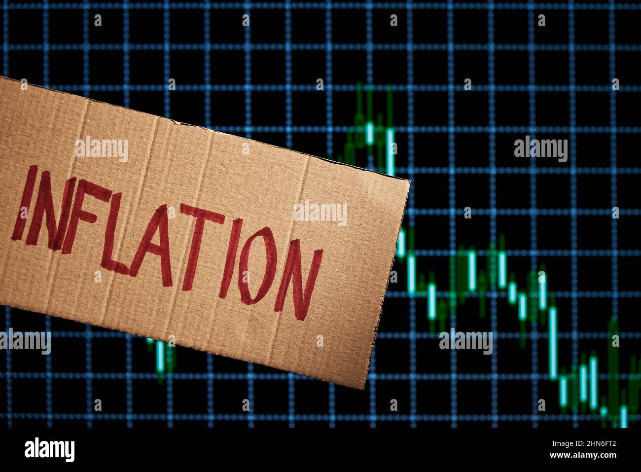 Karton mit Wort Inflation im Hintergrund mit Marktkursdiagramm, Aktienmärkte fallen aufgrund der Inflation Stockfoto