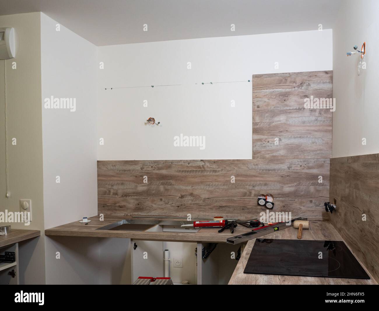 Neue Küche - vorbereitet für die Montage von Küchenmöbeln, Schränken, Spülbecken, Herd, Geschirrspüler. Werkzeuge für die professionelle Montage vorbereitet Stockfoto