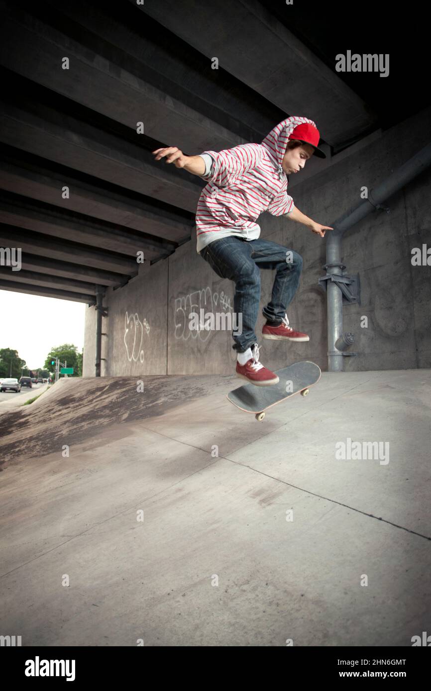 Skateboarder macht einen Kickflip unter Überpass Stockfoto