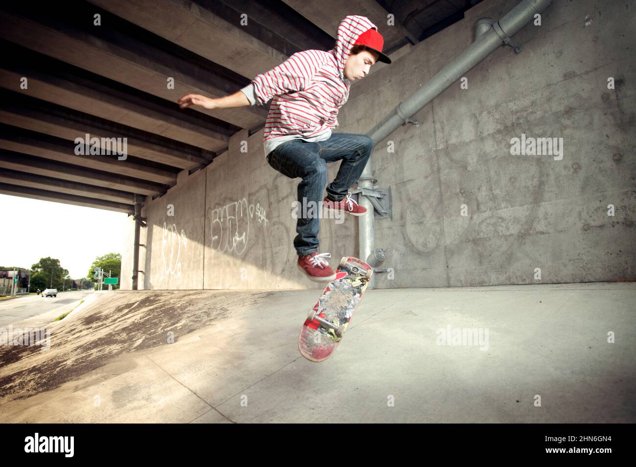Junge männliche Skateboarding unter Überführung Stockfoto