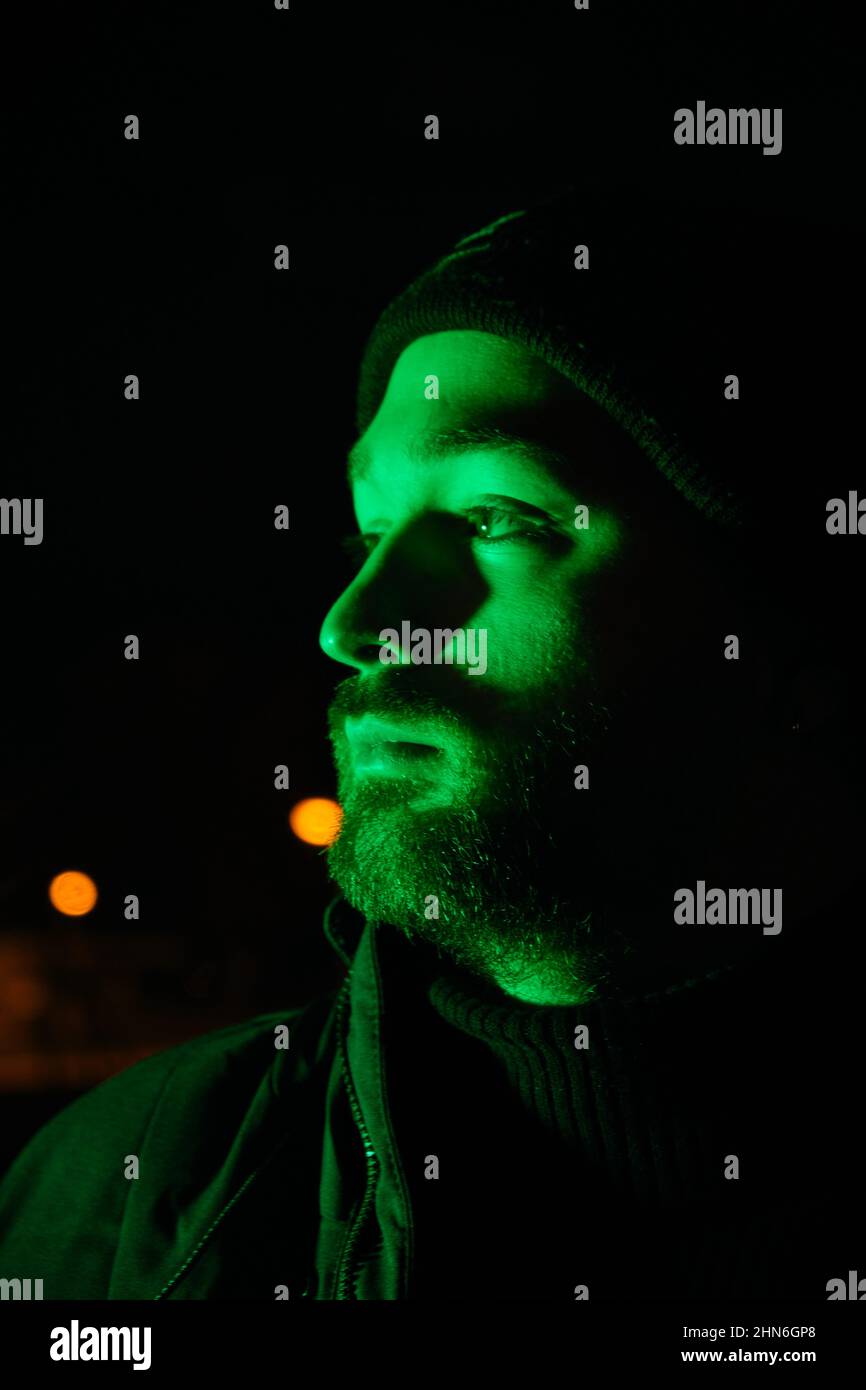 Porträt eines kahlen jungen Mannes, der durch ein grünes Licht beleuchtet fährt Stockfoto