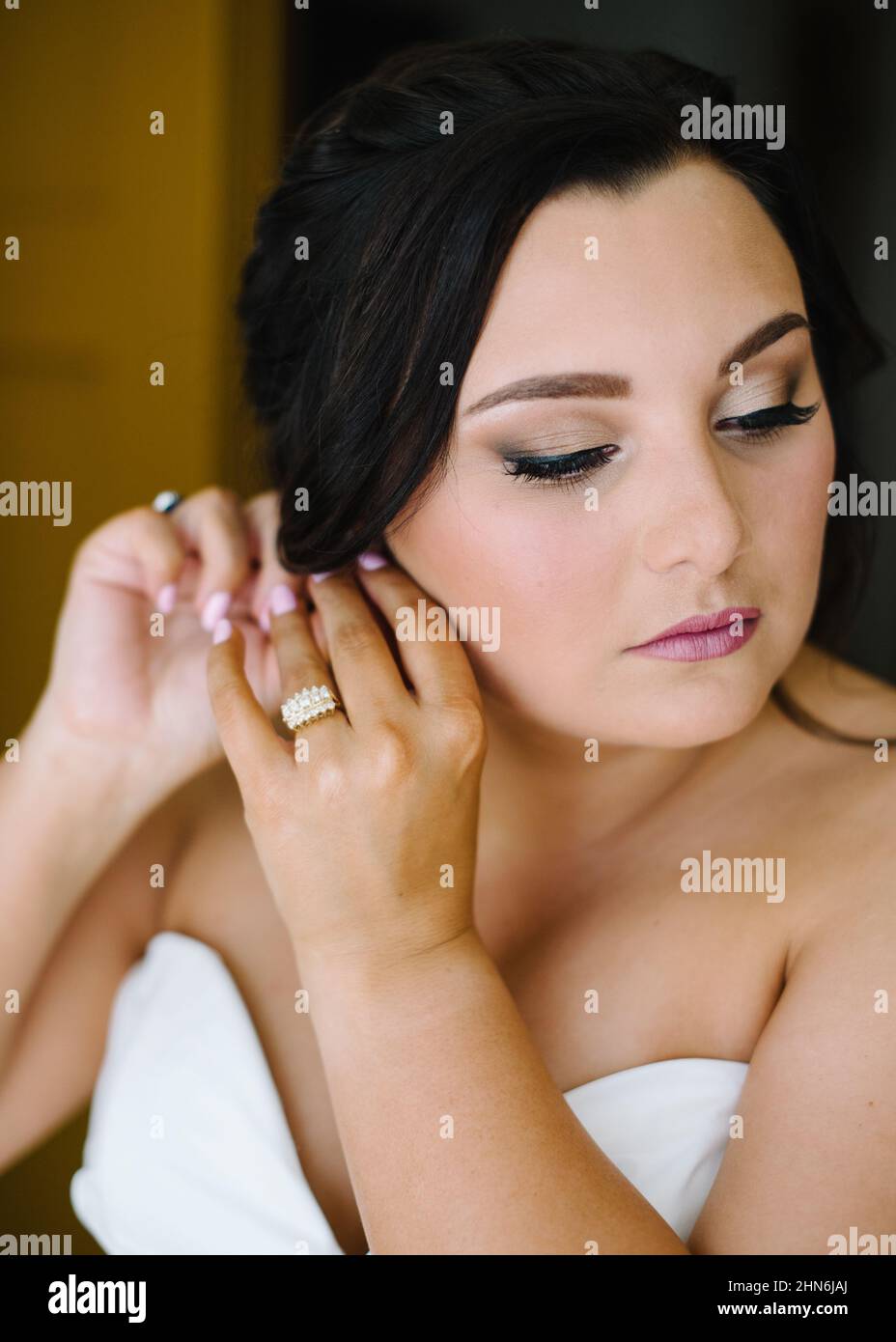 Braut setzt Ohrringe am Hochzeitmorgen ein Stockfoto
