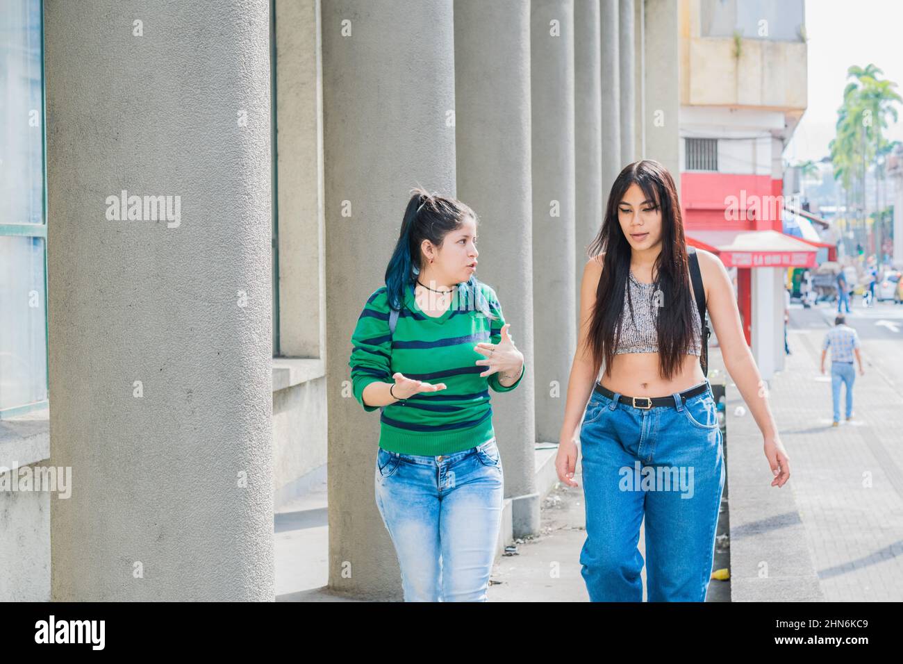 Zwei schöne Latina-Mädchen (kaukasisch und brünett), die die Straße entlang gehen, über ihre Studien reden und über ihre Zukunft diskutieren Stockfoto