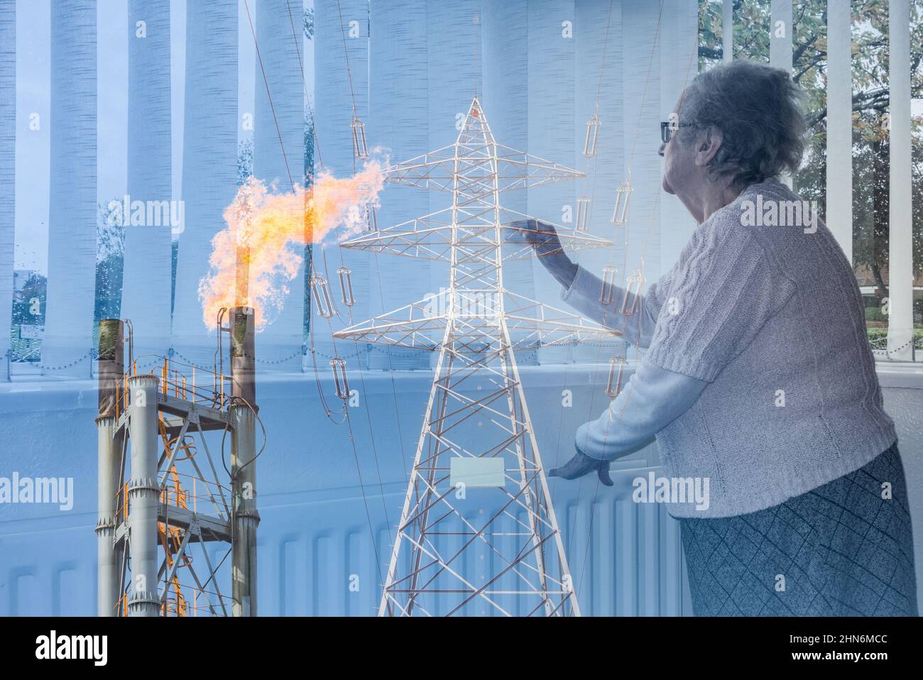 90-jährige Frau, die mit der Hand auf den Heizkörper aus dem Fenster schaute. Strompylon und Industriegas Flare Schornstein Bild gemischt. Energiekrise Konzept. Stockfoto
