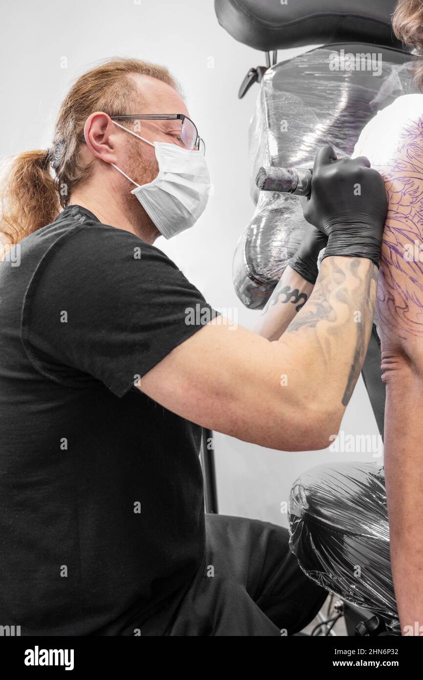 Salontätowierung. Nahaufnahme eines Tätowierers, der arbeitet. Tattoo-Künstler machen Tattoo im Studio. Hochwertige Fotografie. Stockfoto