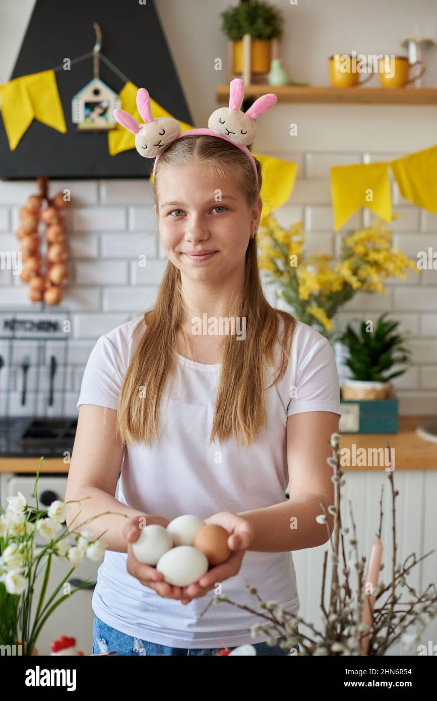 Mädchen 12 Jahre alt hält Ostereier in der Küche. Stockfoto