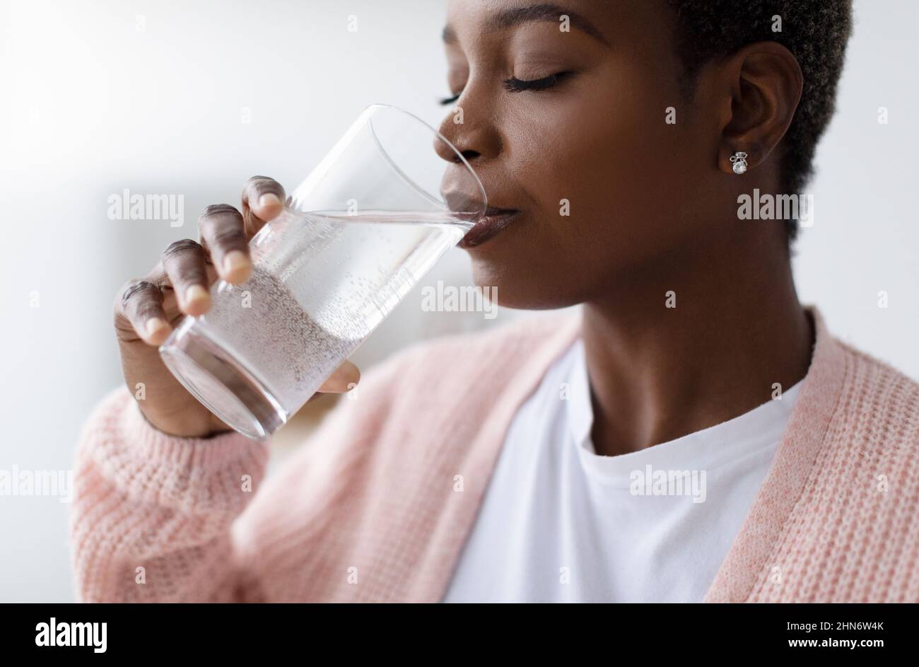 Millennial african american Dame in casual trinken Wasser aus Glas in Küche Innenraum, Profil, Nahaufnahme Stockfoto