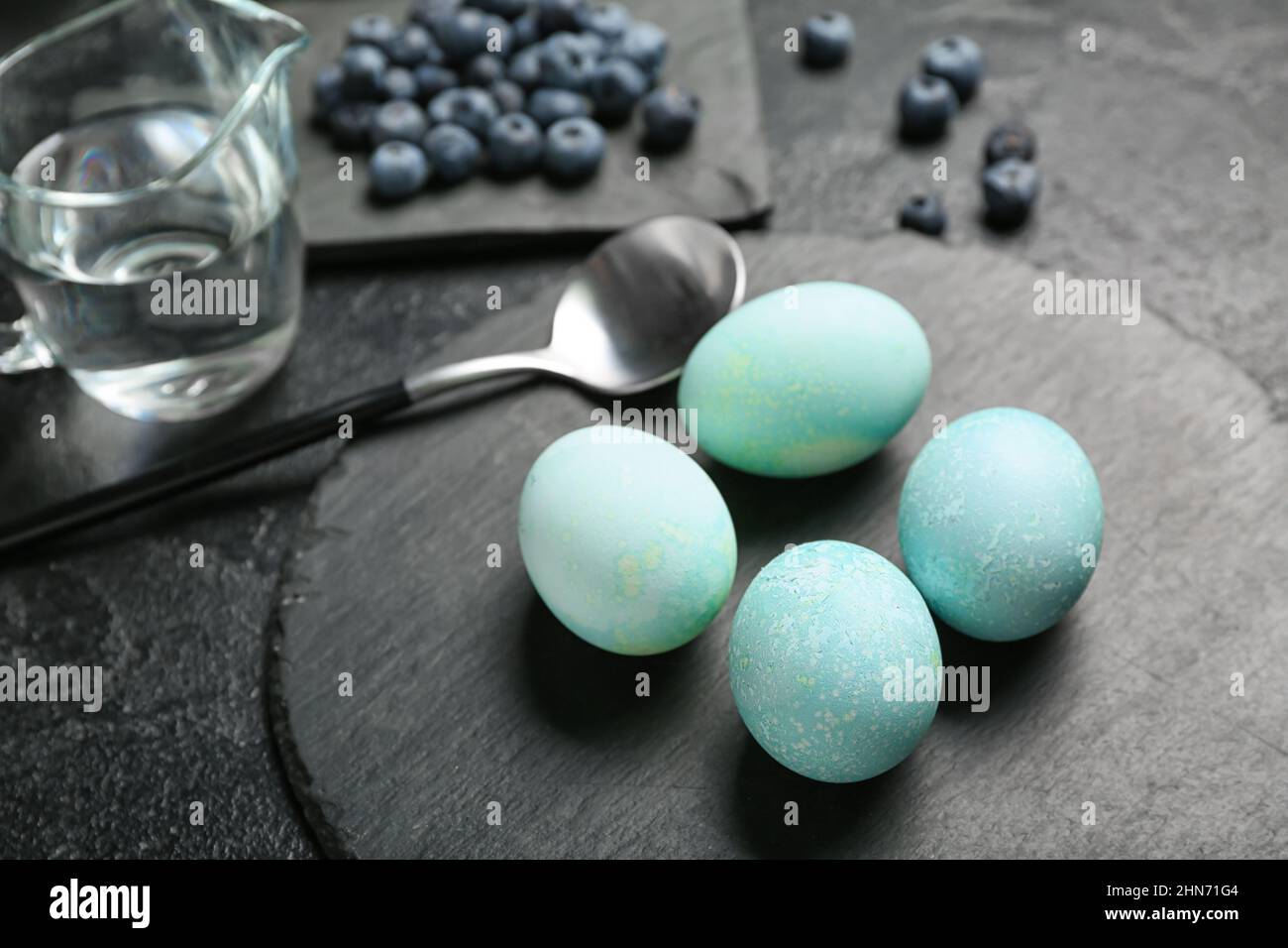 Natürlich gefärbte Ostereier und Heidelbeere auf dunklem Tisch, Nahaufnahme Stockfoto