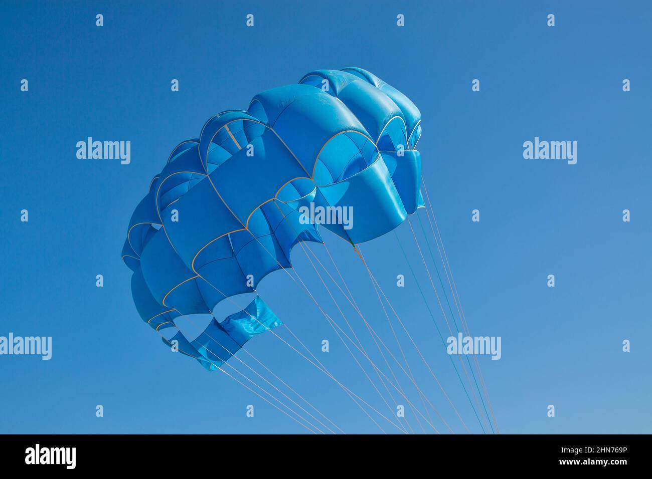 Blauer, offener Fallschirm für Paragliding-Wassersportarten gegen den klaren blauen Himmel Stockfoto
