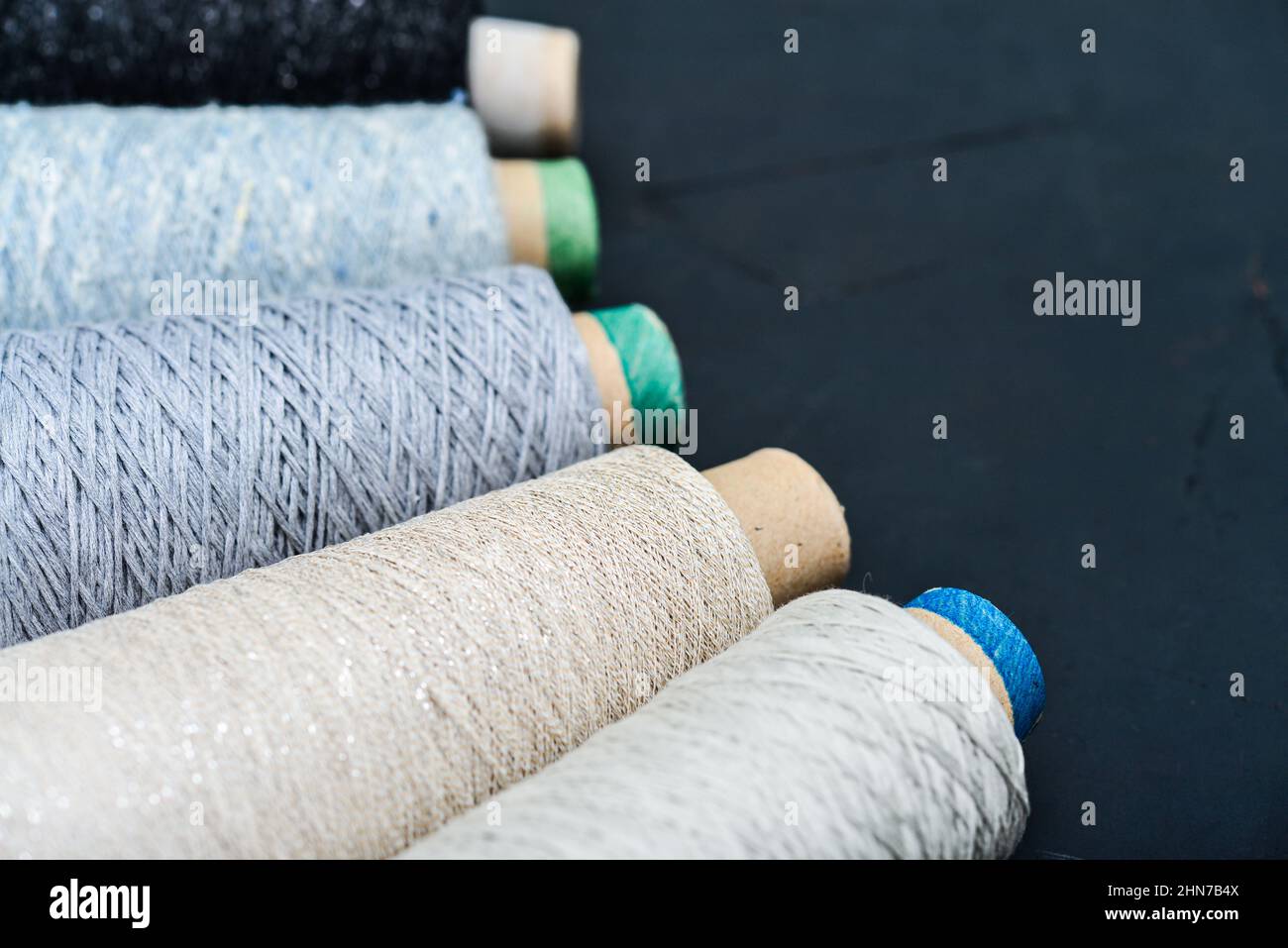 Set aus farbigem Garn zum Stricken auf Kegel auf schwarzem Hintergrund, Draufsicht Stockfoto
