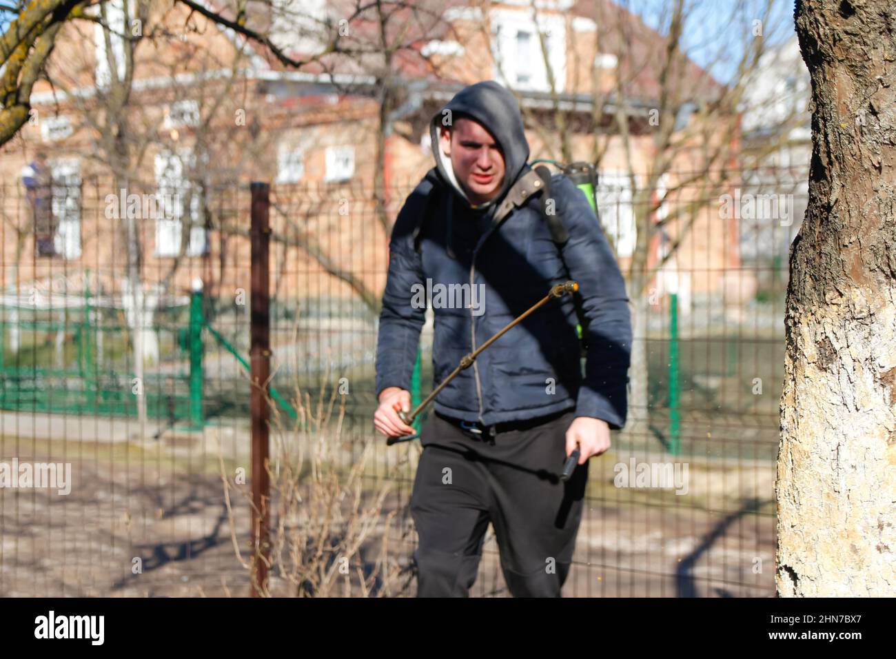 Ökologische ökologische Landwirtschaft. Unschärfe Landwirt Mann sprühen Baum mit manuellen Pestizid-Sprüher gegen Insekten im Frühlingsgarten. Landwirtschaft und Stockfoto