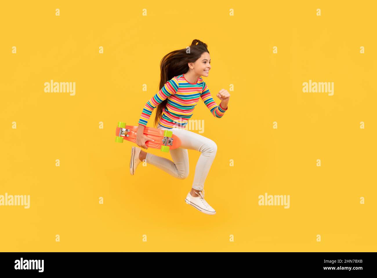 Glücklich energetische Kind Skateboarder springen mit Penny Board Skateboard, Kindheit Stockfoto