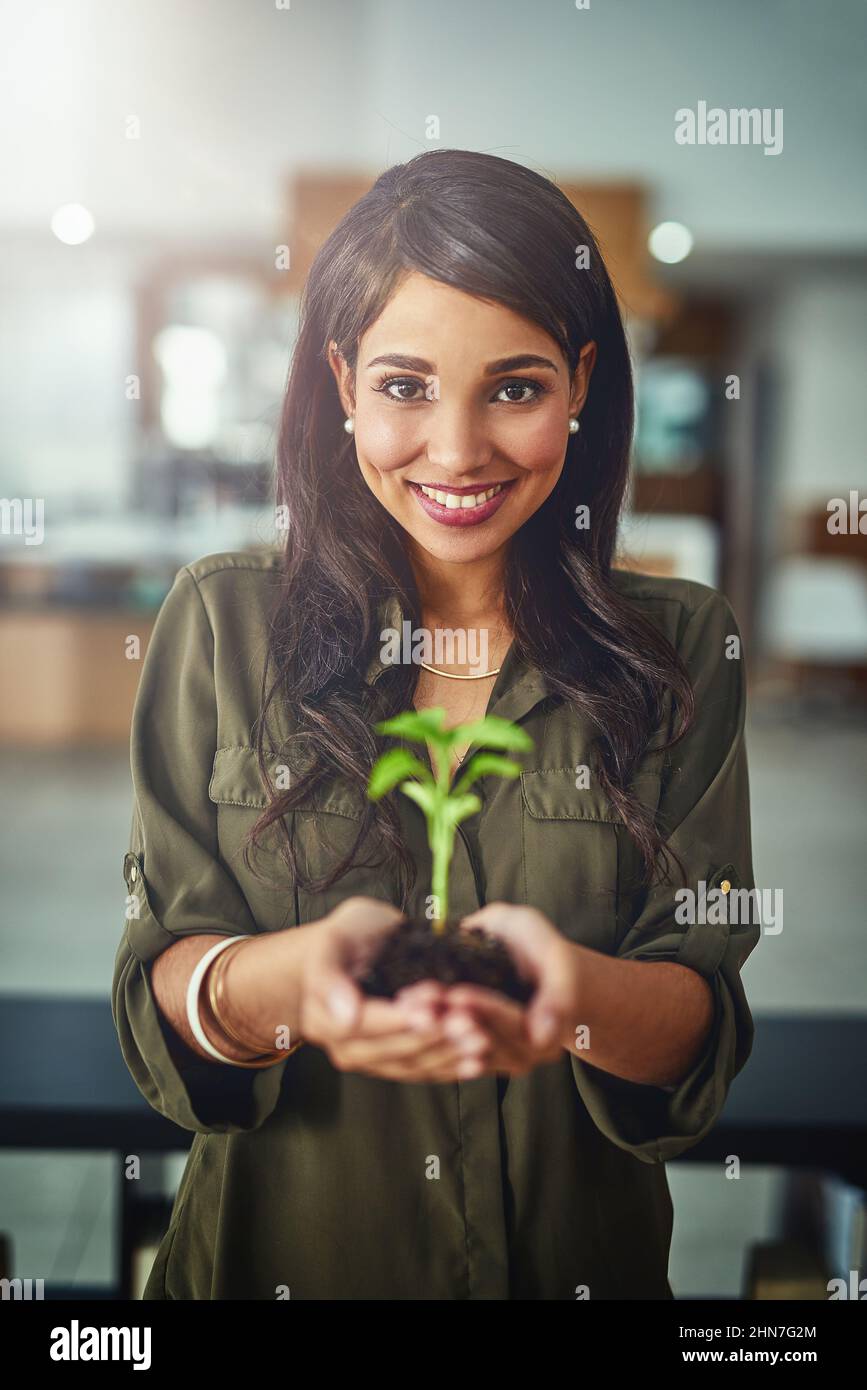 Fangen Sie klein an, aber wachsen Sie hoch. Porträt einer jungen Geschäftsfrau, die eine im Boden wachsende Pflanze hält. Stockfoto