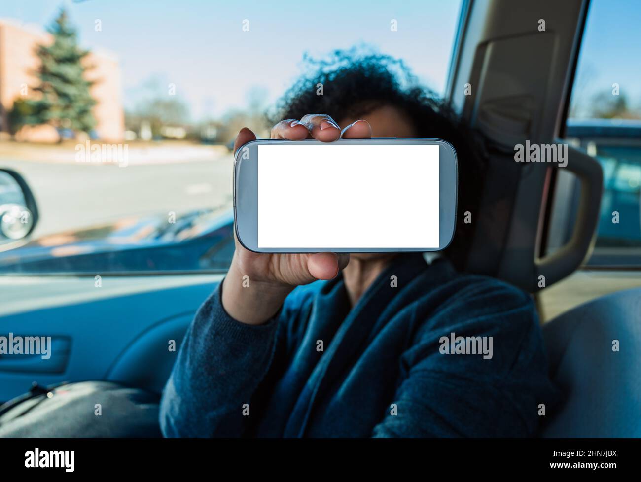 Modell der Telefonanwendung im Auto. Weibliche Hand hält den weißen leeren Bildschirm des Mobiles. Text für Leerzeichen kopieren. Selektiver Fokus. Stockfoto