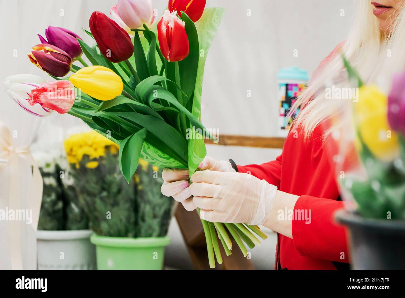 Frau Floristin macht Bouquet von frischen Tulpen. Die Hände halten Frühlingsblumen. Kleines Geschäft für Gärtner, Blumengeschäft. Stockfoto