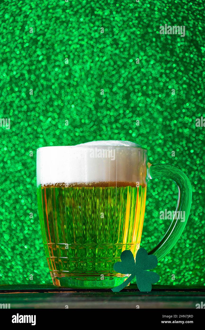 Becher helles Bier mit Schaum auf grünem Hintergrund. Traditionelles irisches Getränk. Wir feiern den St. Patrick's Day. Stockfoto