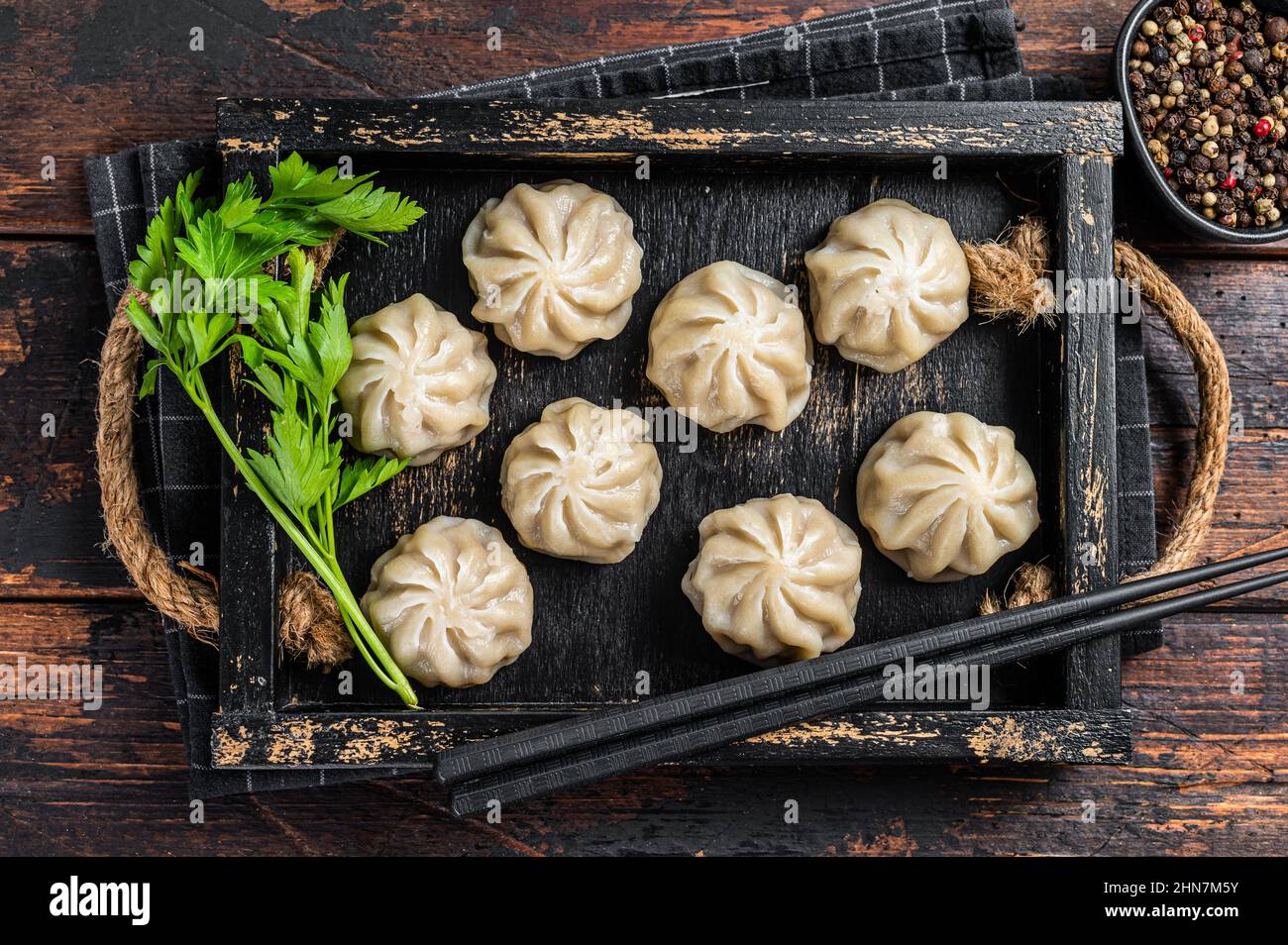 Momo Knödel in einem Holztablett mit Kräutern. Dunkler Holzhintergrund. Draufsicht Stockfoto