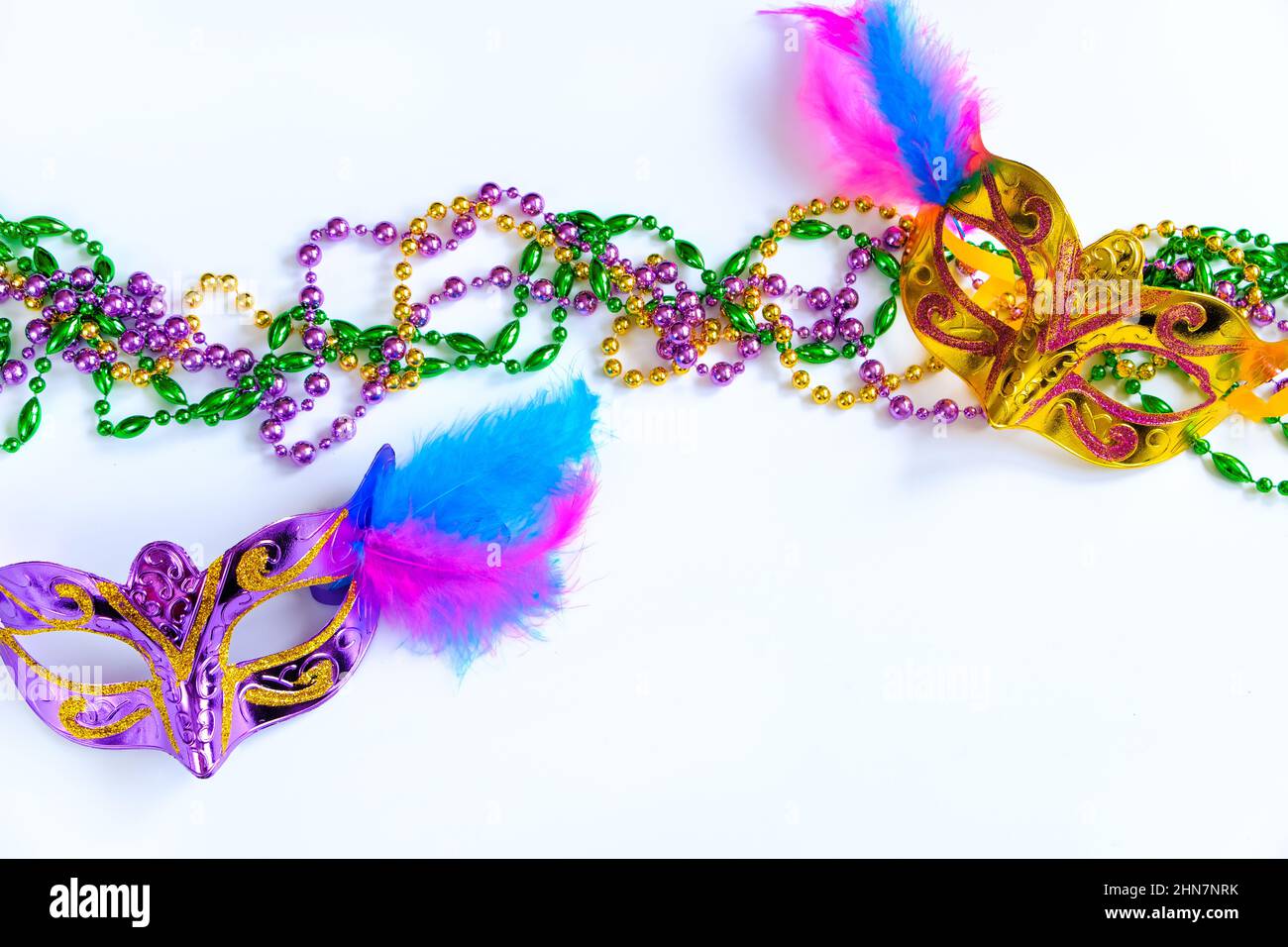 Zwei Karnevalsmasken mit Federn und bunten Perlen auf weißem Hintergrund. Symbol „Mardi Gras“ oder „Fat Tuesday“. Grußkarte für traditionelle holi Stockfoto