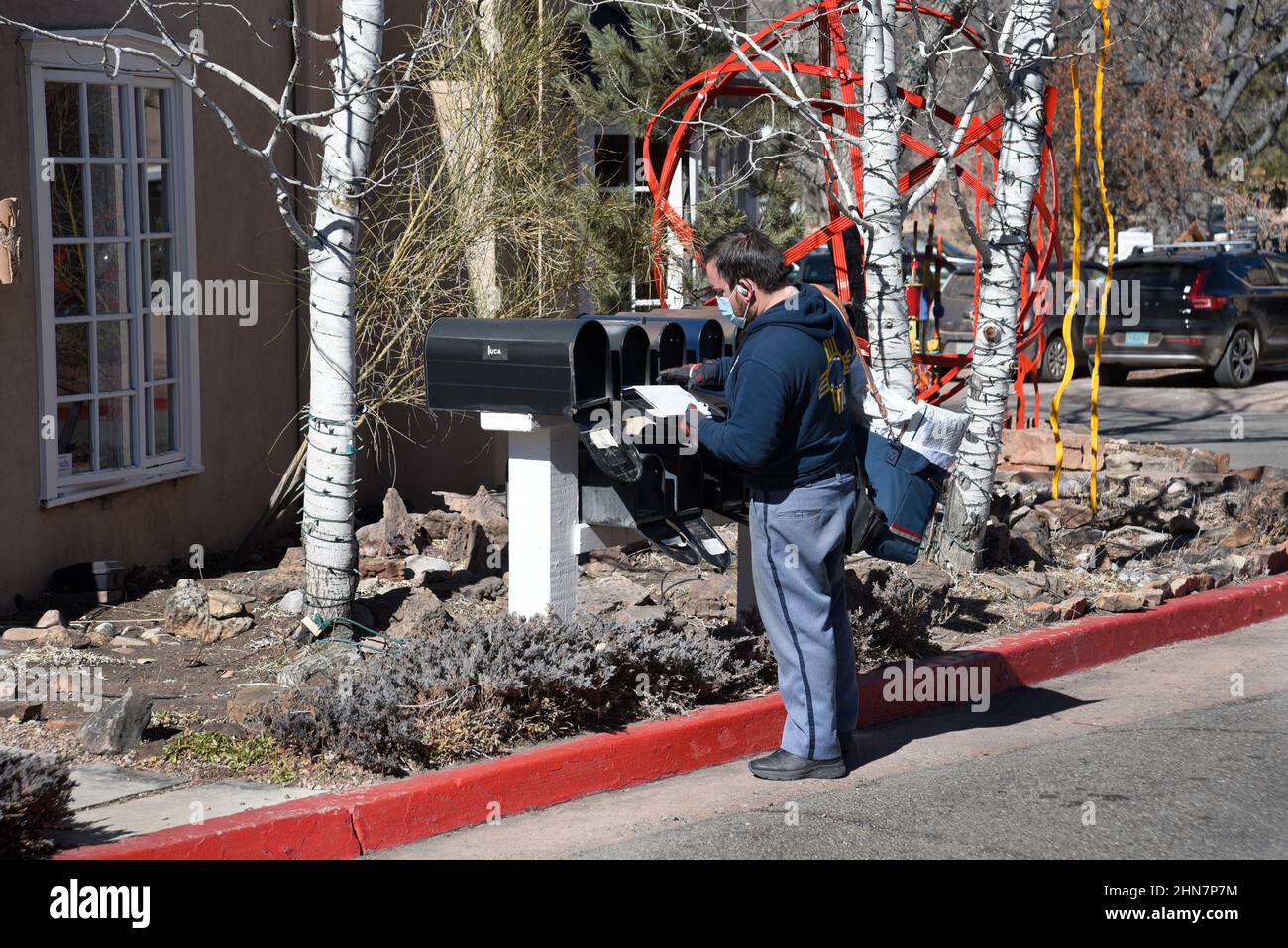 Ein amerikanischer Postbote oder Briefträger liefert Post an eine Reihe von Postfächern in Santa Fe, New Mexico. Stockfoto