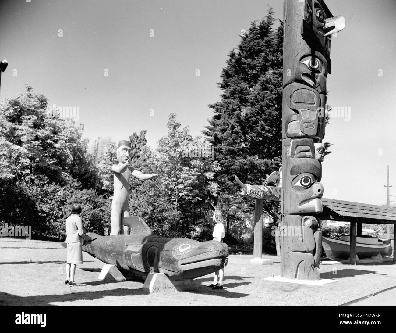 Vintage Schwarz-Weiß-Fotografie von zwei Frauen, die Totempfähle und Skulpturen der Northwest Coast im Thunderbird Park Ca. 1940 in Victoria, British Columbia, Kanada Stockfoto