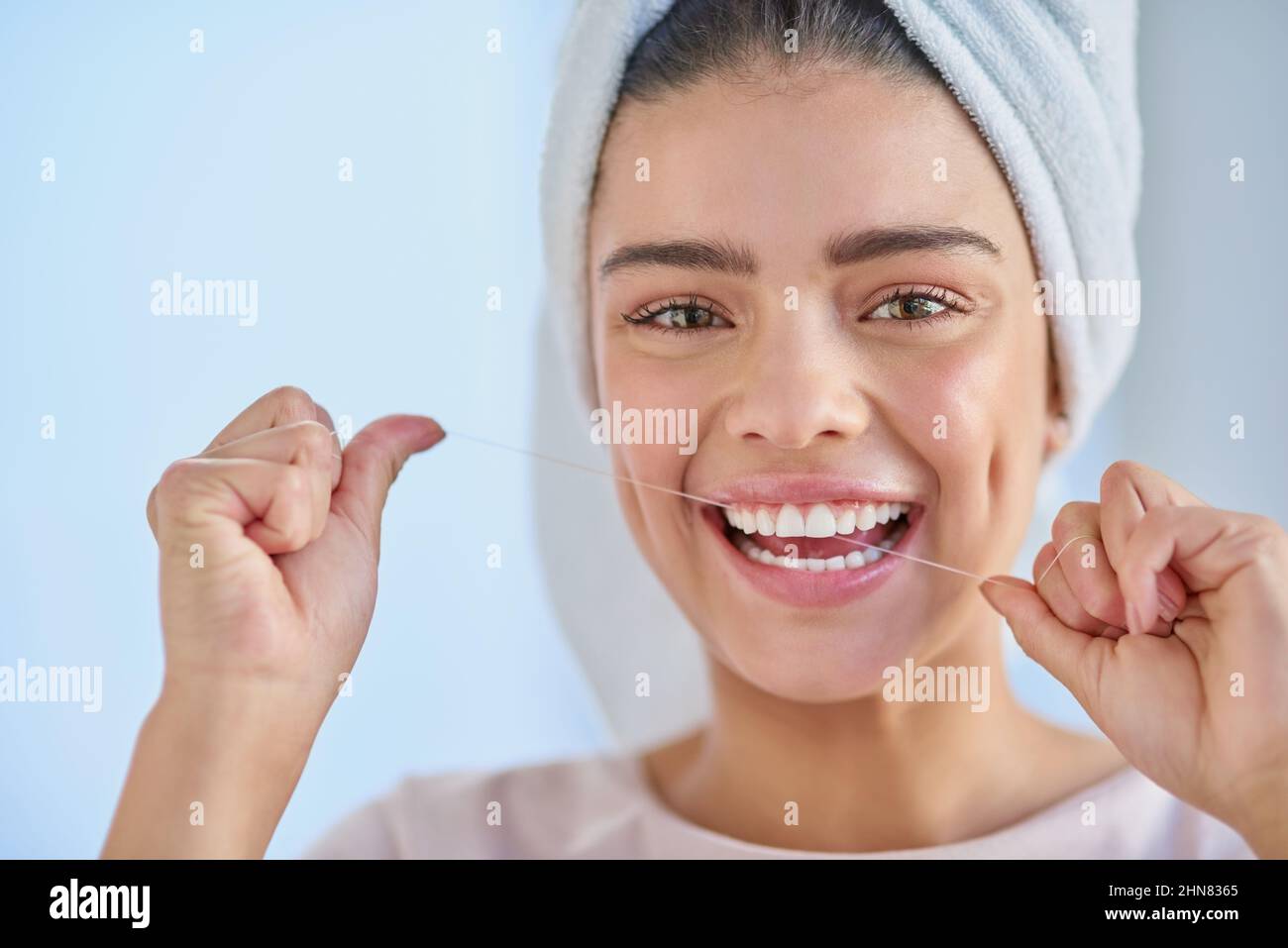 Kümmere mich um mein Lächeln. Ein Porträt einer schönen jungen Frau, die zu Hause im Badezimmer ihre Zähne mit Zahnseide putzt. Stockfoto