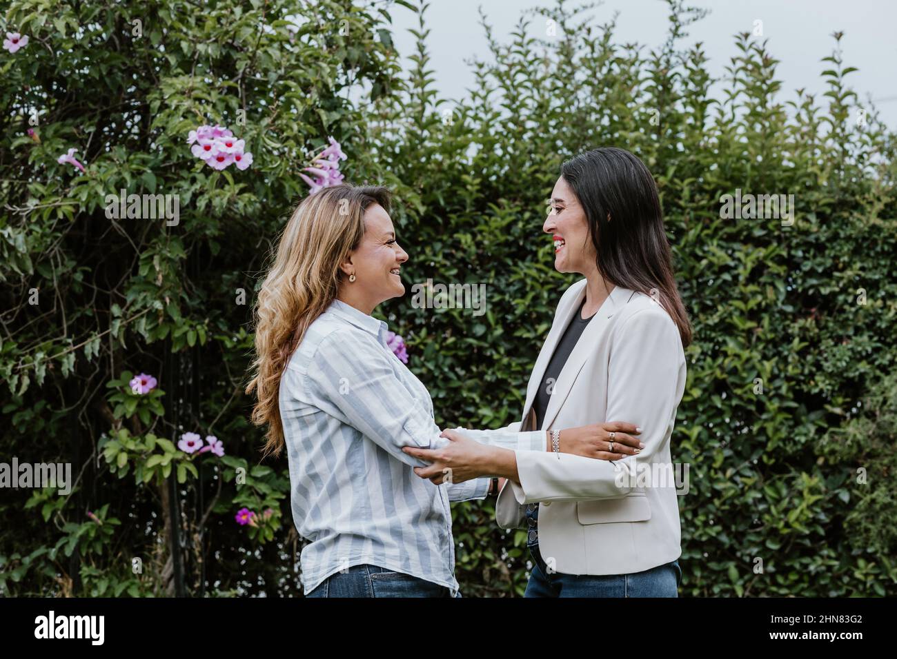 Zwei lateinamerikanische Freundinnen umarmen sich im Terrassenbüro in Mexiko, Lateinamerika Stockfoto