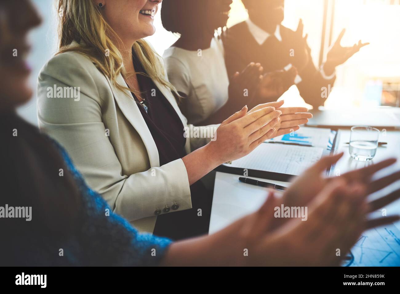 Die Zufriedenheit der Mitarbeiter führt zu einem positiven Ambiente am Arbeitsplatz. Ausgeschnittene Aufnahme einer Gruppe von Geschäftsleuten, die einer Unternehmenspräsentation applaudieren. Stockfoto