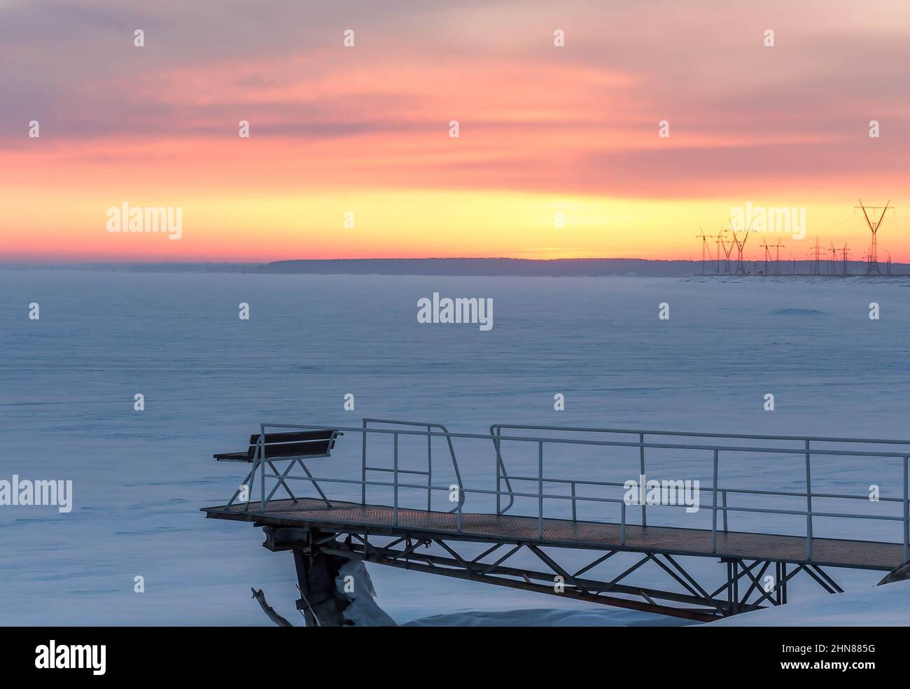 Pier am gefrorenen Stausee bei Sonnenuntergang. Winterabend Goldener Himmel bei Sonnenuntergang, schneebedeckte Ebene, gefrorener Nowosibirsker Stausee am ob-Fluss in der Nähe von Nowosibirs Stockfoto
