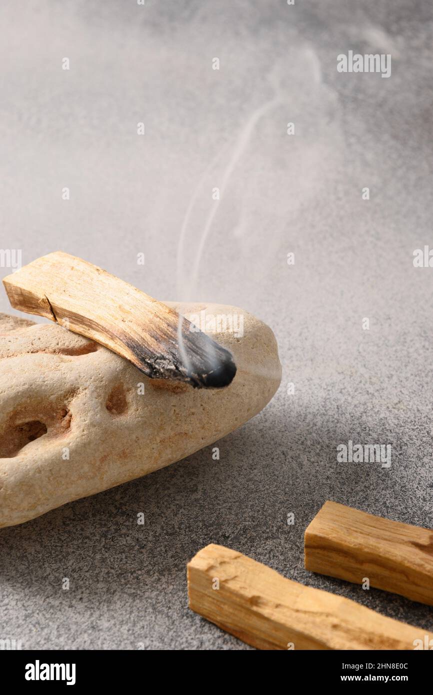 Palo Santo Räucherstäbchen, die auf Stein brennen. Heiliges Holz Rauch. Spirituelle Praktiken. Vertikales Format. Nahaufnahme. Stockfoto