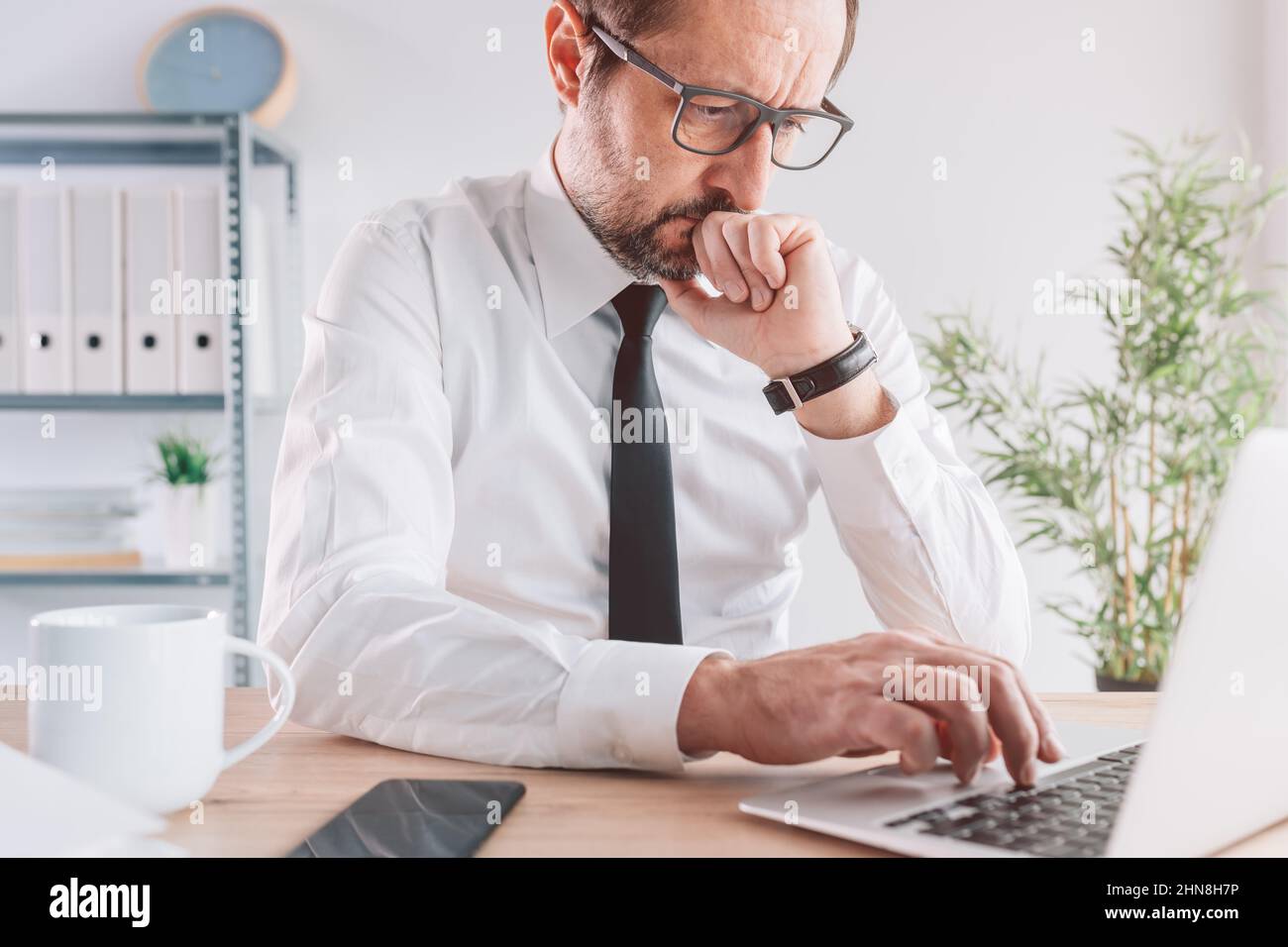 Geschäftsleute, die an einem Laptop-Computer in hellen Büroräumen arbeiten, ernsthaft unternehmerisches Denken, Porträt mit selektivem Fokus Stockfoto