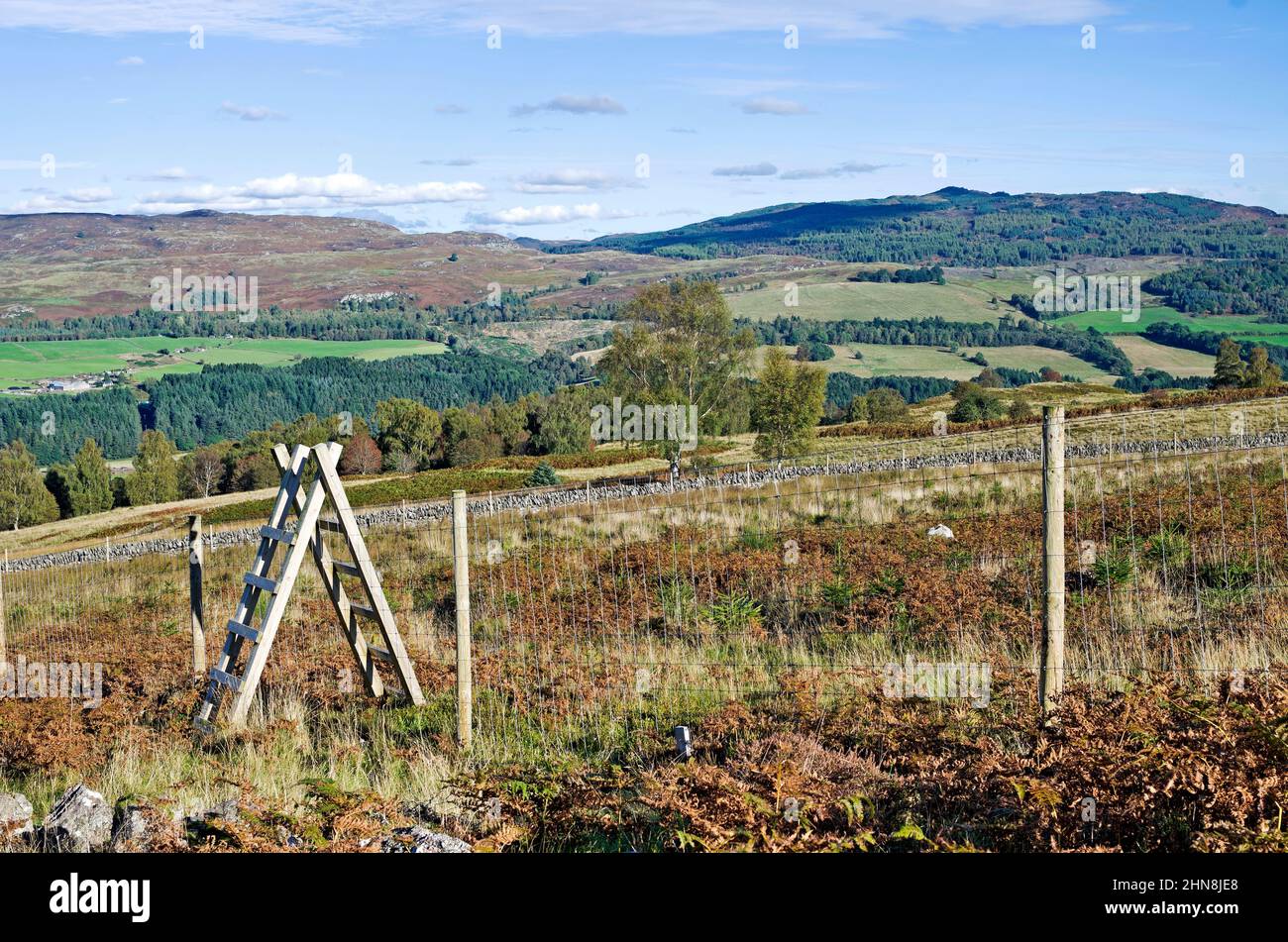 Holzstile über dem Hirschzaun in rauem Moorland, Tayside, Perthshire, mit Blick auf Ackerland und Hügel auf der gegenüberliegenden Talseite, Herbst, Schottland Stockfoto