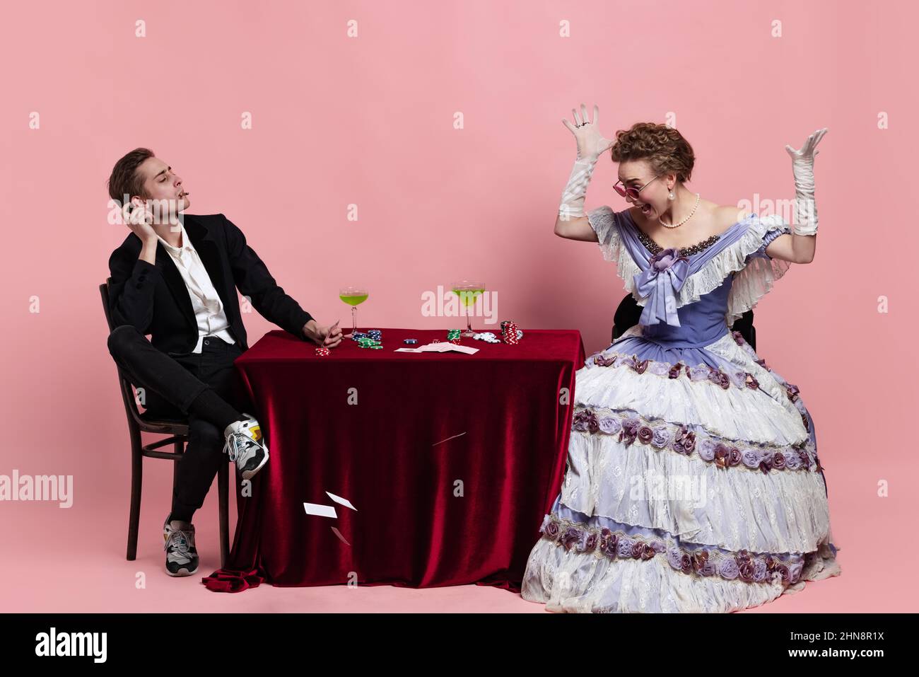 Portrait der jungen schönen Frau im Bild der mittelalterlichen königlichen Person in Abendkleid mit Diener, Page-Boy spielen isoliert auf rosa Hintergrund Stockfoto