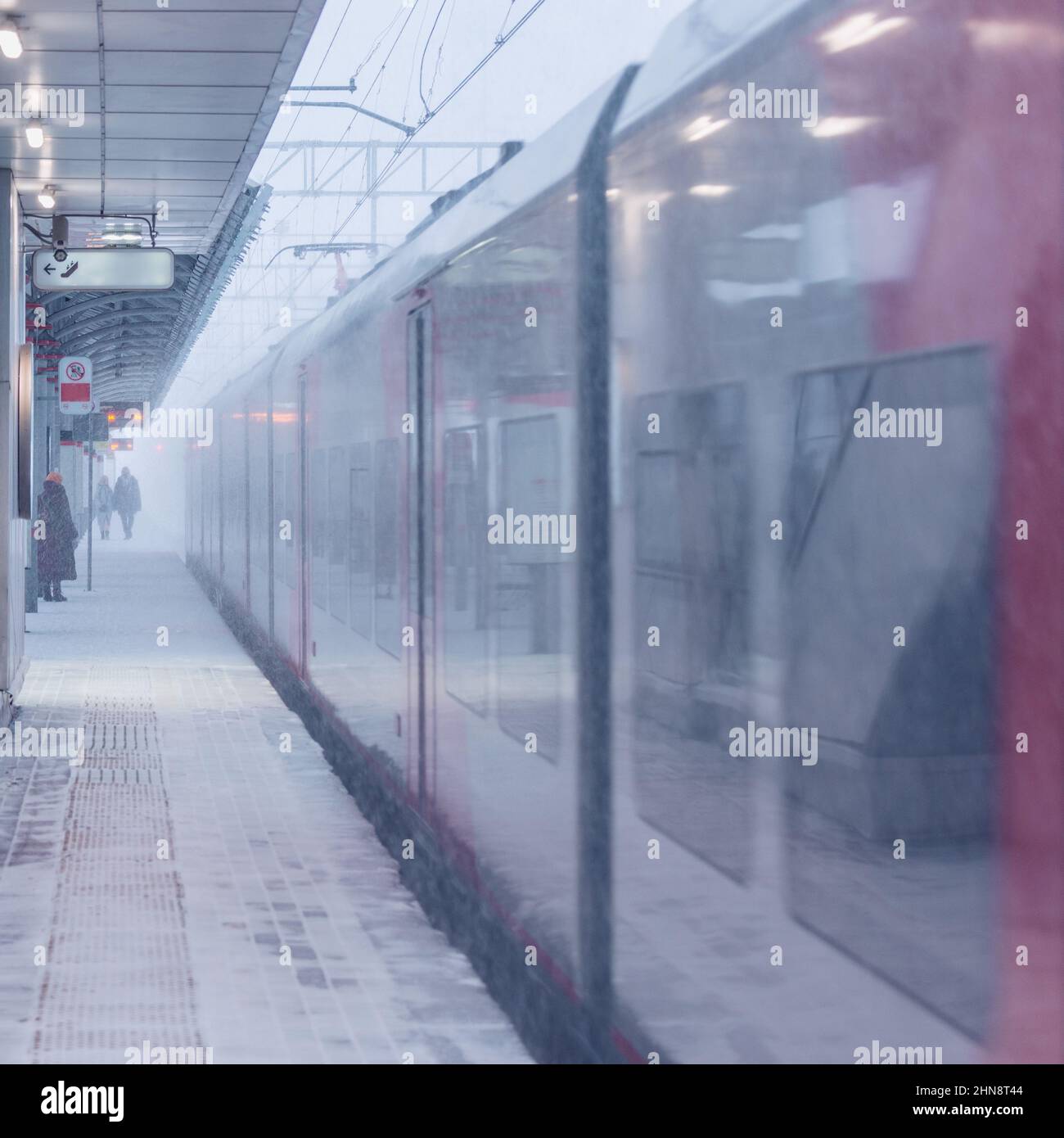 Der Hochgeschwindigkeitszug fährt bei Schneesturm vom Bahnsteig ab. Stockfoto