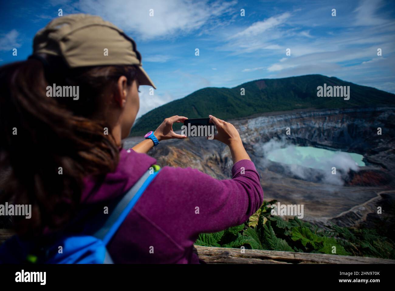 Junge Frau fotografiert den Vulkan Poas, einen aktiven 2.697 Meter langen Stratovulkan in Zentral-Costa Rica, der sich im Nationalpark des Vulkans Poas befindet Stockfoto