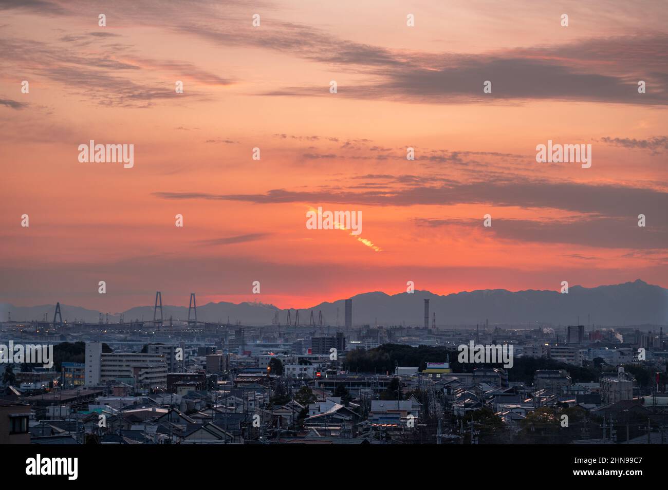 Sonnenuntergang am roten Himmel, Übersicht von einem hohen Ort. Die japanische Stadt Nagoya mit Bergen im Hintergrund. Stockfoto