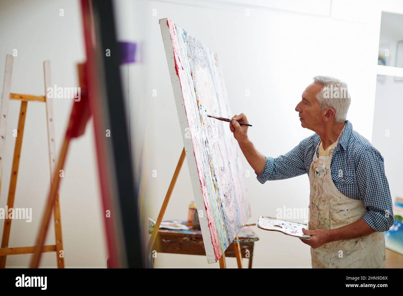 Macher machen. Aufnahme eines älteren Mannes, der zu Hause an einem Gemälde arbeitet. Stockfoto