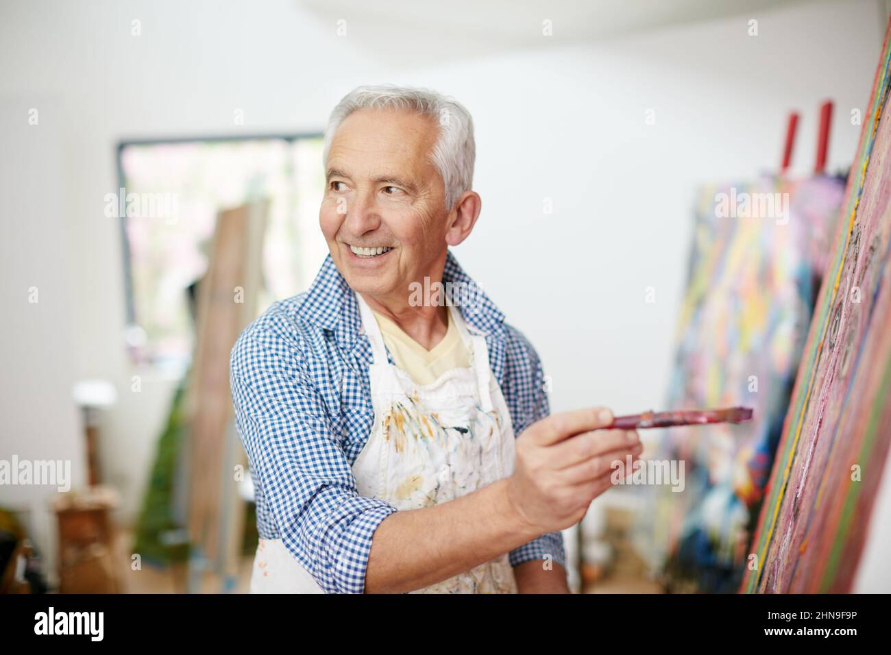 Künstler zu sein bedeutet, an das Leben zu glauben. Aufnahme eines älteren Mannes, der zu Hause an einem Gemälde arbeitet. Stockfoto