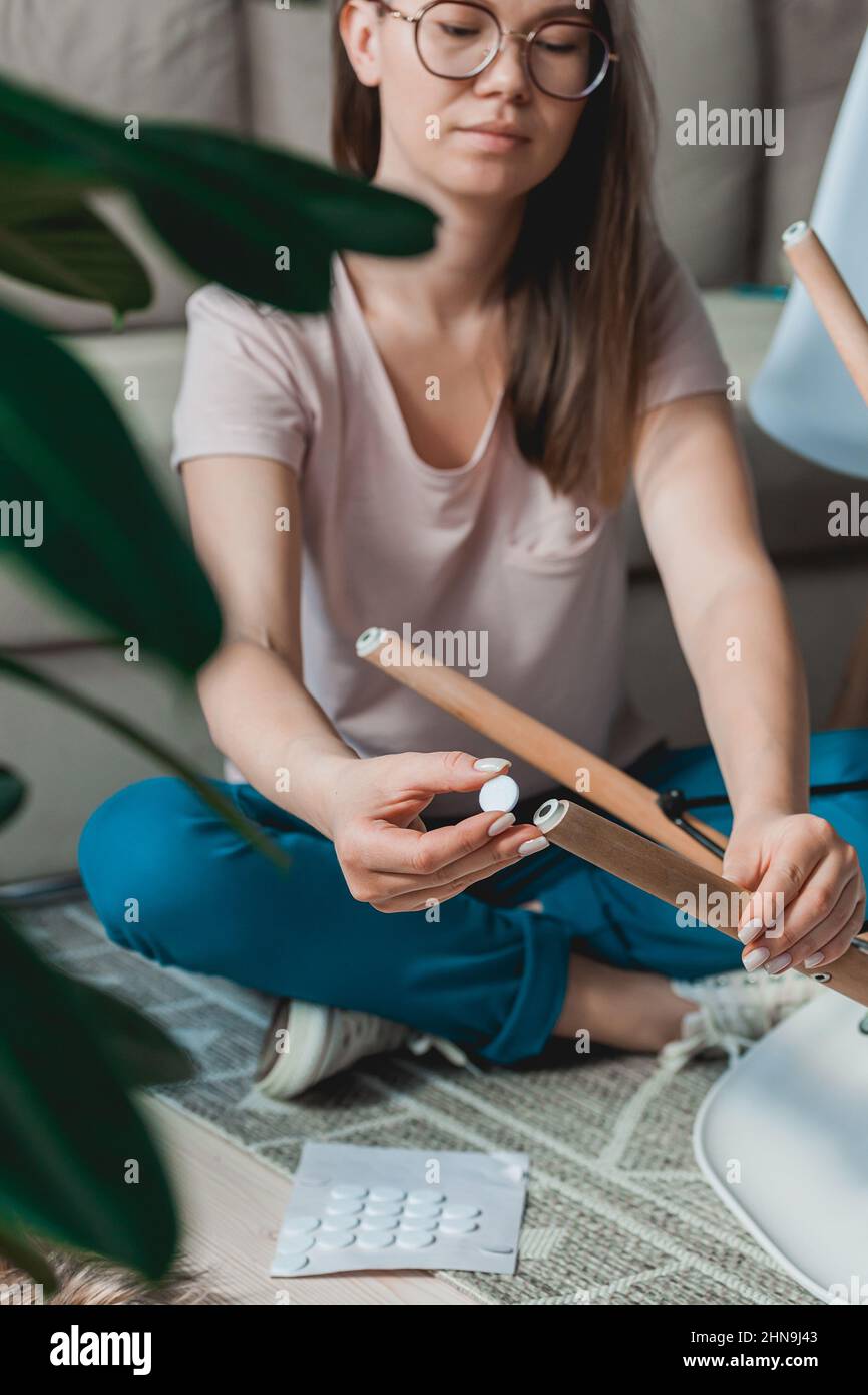 Frau befestigen Filzkissen auf Stuhlbein, Pflege des Bodens Stockfoto
