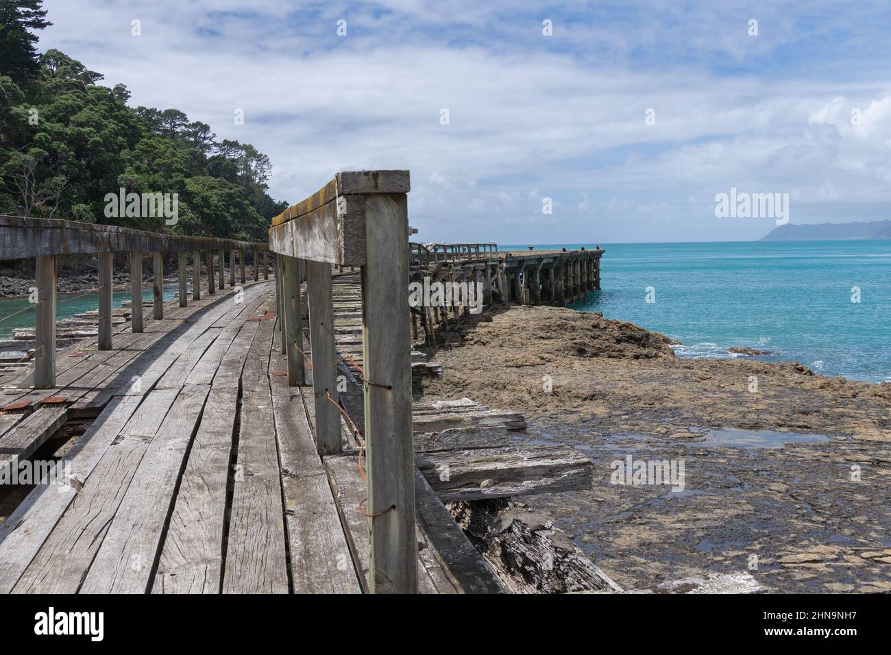 Überreste eines alten Anlegesteg oder Anlegesteg, der sich von Land an der Hicks Bay an der Ostküste auf der Nordinsel Neuseelands erstreckt. Stockfoto