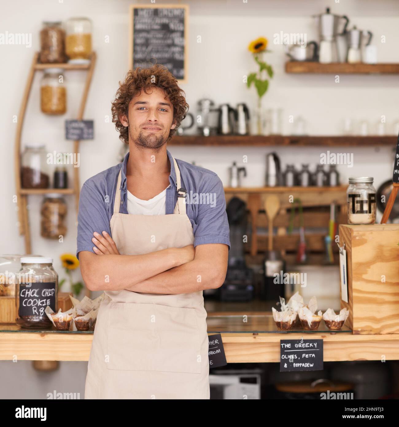Immer ein freundliches Gesicht im Café. Porträt eines Baristas, der fröhlich an einem Café-Tresen steht. Stockfoto