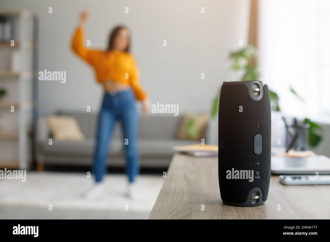 Millennial Frau tanzt zu Lieblingsmusik zu Hause, selektiver Fokus auf tragbare kabellose Lautsprecher, freier Platz Stockfoto
