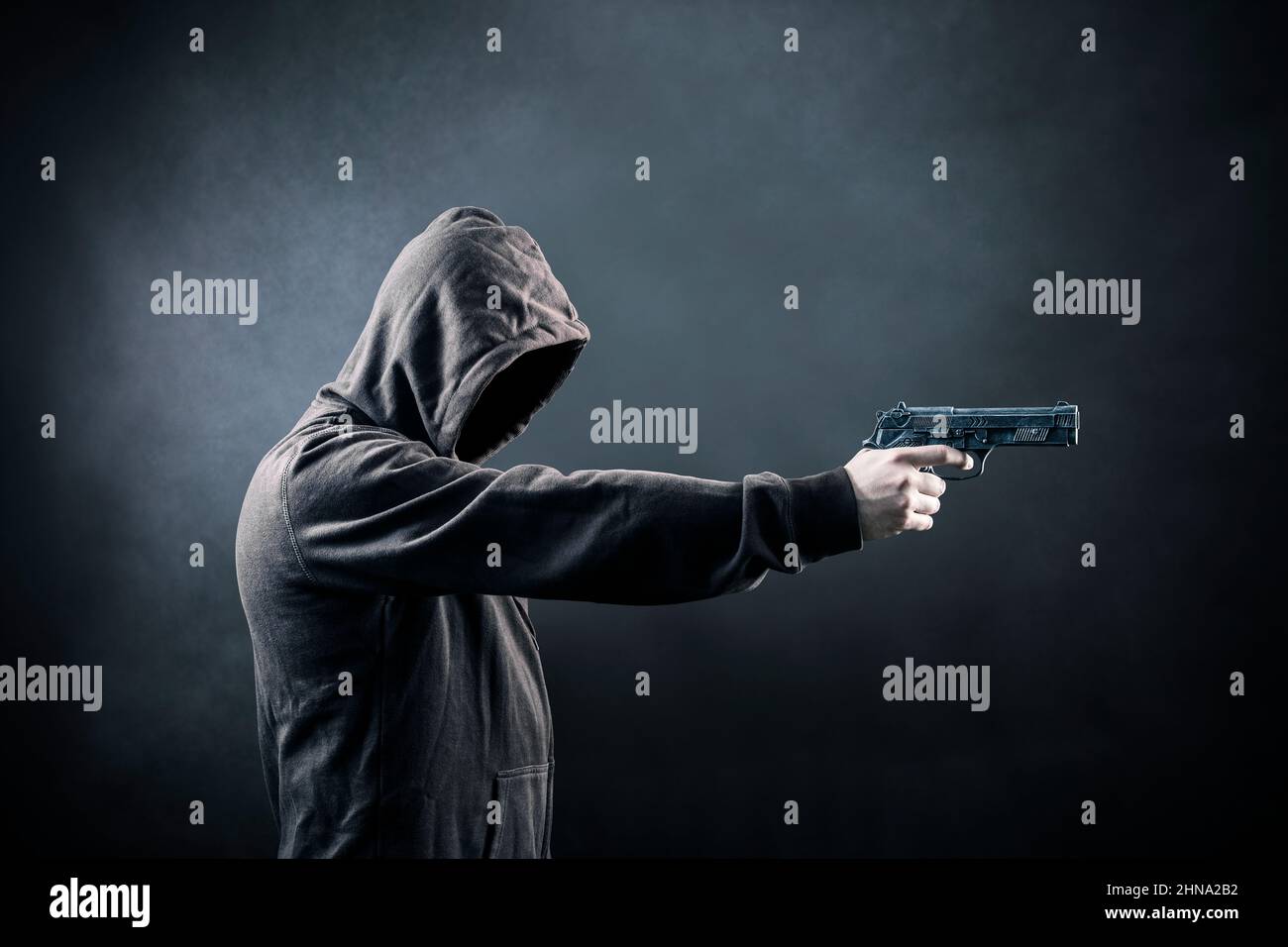 Mit Kapuze Mann mit einer Pistole in der Dunkelheit Stockfoto